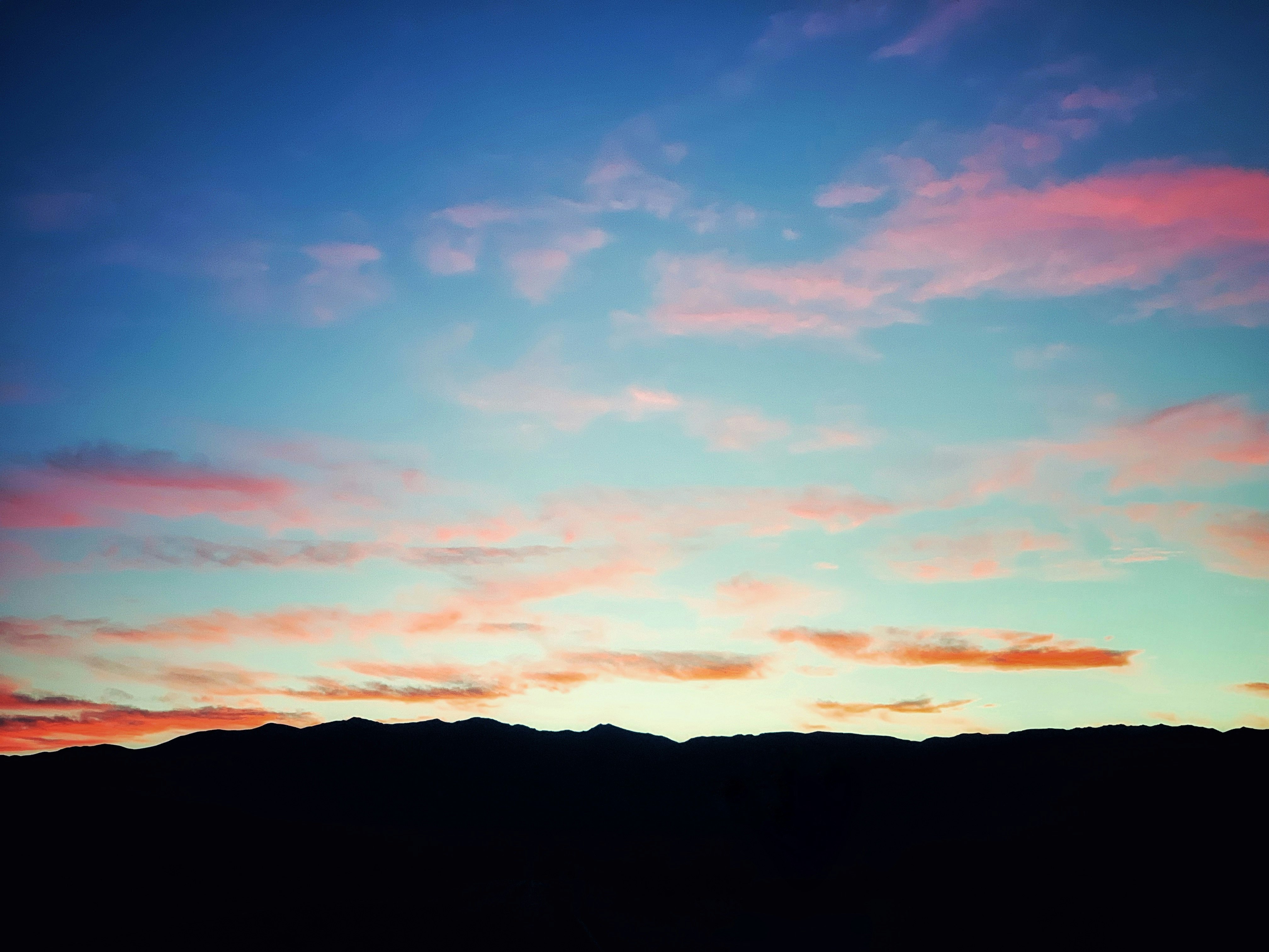 silhouette of mountains under red clouds and blue sky